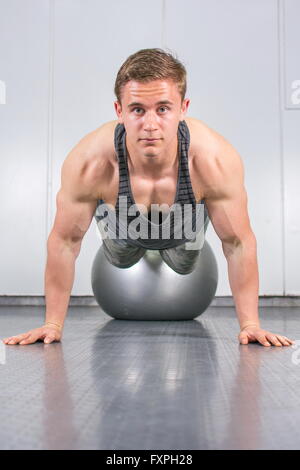 Giovane uomo di eseguire push up con sfera di pilates Foto Stock