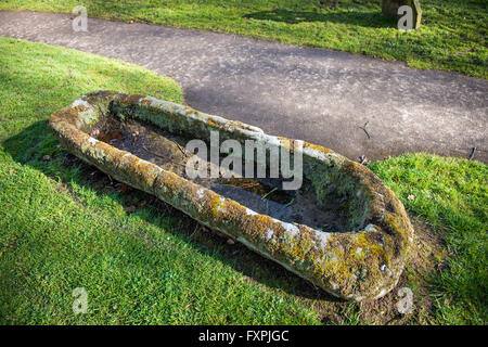 Un solido sarcofago di pietra nel cimitero della Chiesa di San Pietro, affacciato sulla baia di Morecambe situata a Heysham, Lancashire, Regno Unito Foto Stock