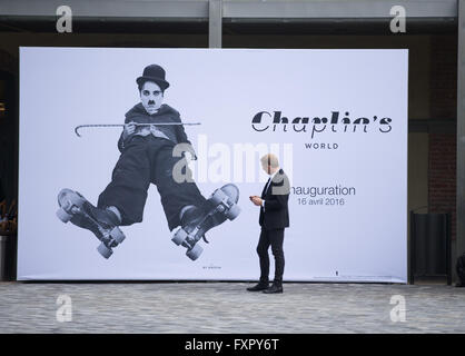 Ginevra, Svizzera. Xvi Apr, 2016. Un uomo è in piedi di fronte a un enorme poster di Chaplin accanto alla entrata di Chaplin del mondo nel Museo di Corsier-sur-Vevey, Svizzera occidentale, il 16 aprile 2016. Chaplin World Museum, la presentazione della vita e delle opere di legenda schermo Charlie Chaplin, è stata inaugurata a Corsier-sur-Vevey village per contrassegnare il 127º anniversario di Charlie Chaplin nascita. Corsier-sur-Vevey è stata la casa di Charlie Chaplin e la sua famiglia negli ultimi venticinque anni della sua vita. © Xu Jinquan/Xinhua/Alamy Live News Foto Stock