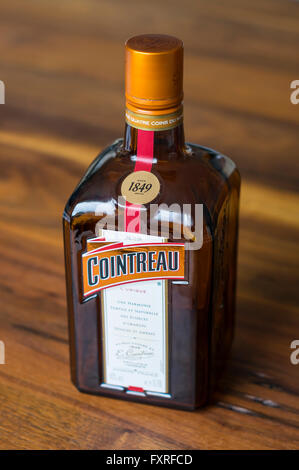 Bottiglia di Cointreau triple sec (un arancione-liquore aromatizzato) su un tavolo di legno. Profondità di campo focalizzato sul logo. Foto Stock
