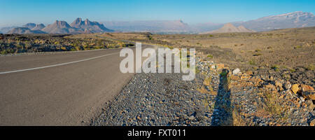 Autostrada attraverso deserto ruvido in Al Hajar mountain range, Oman. Foto Stock