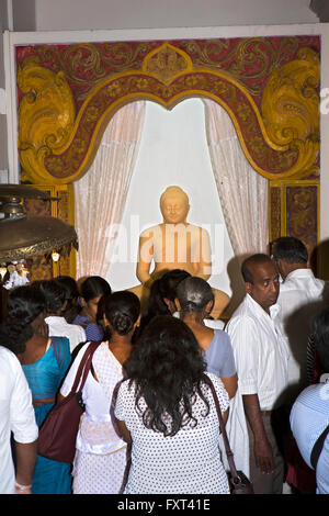 Sri Lanka, Kandy, tempio del Dente, sala da preghiera devoti pregando in nuova pietra scolpita statua del Buddha Foto Stock