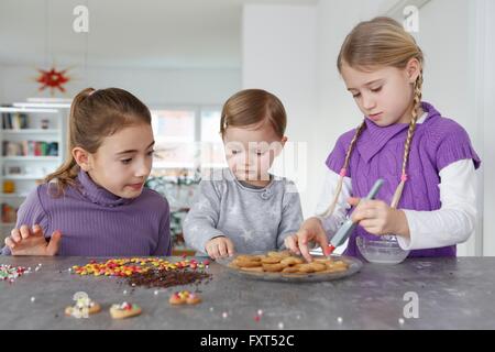 Le ragazze al bancone cucina decorare i cookie Foto Stock