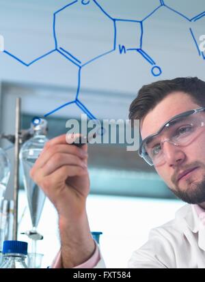 Scienziato maschio che illustra antibiotico formula chimica in Pharmaceutical Research Lab Foto Stock