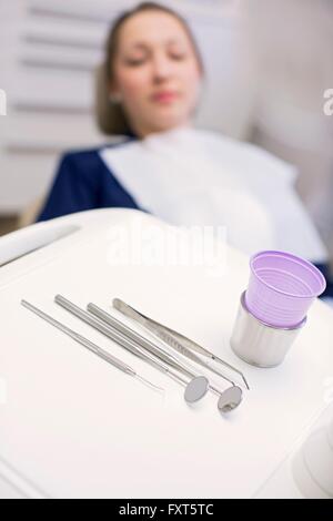 Giovane donna in poltrona del dentista in attesa di esame dentale guardando apparecchiatura dentale Foto Stock