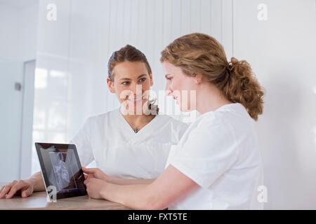 Dentisti guardando a tavoletta digitale con raggi x immagine sullo schermo, sorridente Foto Stock