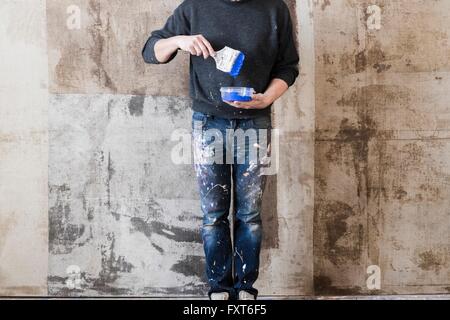 Uomo con spazzola di vernice su un contenitore di plastica in mano Foto Stock