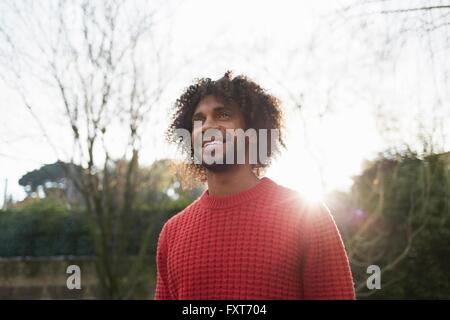 Uomo che indossa red maglione di lana che guarda lontano sorridente Foto Stock