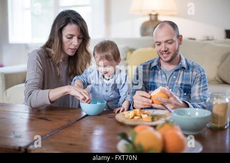 I genitori a pranzo con baby boy, peeling arancione Foto Stock