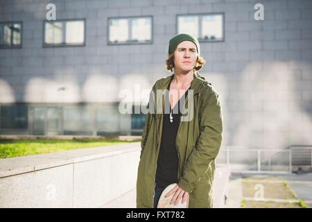 Ritratto di giovane maschio urban skate boarder fuori ufficio edificio Foto Stock