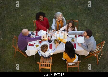 Vista aerea del multi generazione famiglia mangiare all'aperto, rendendo un toast sorridente Foto Stock