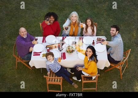 Vista aerea del multi generazione famiglia mangiare all'aperto osservando la telecamera, rendendo un toast sorridente Foto Stock