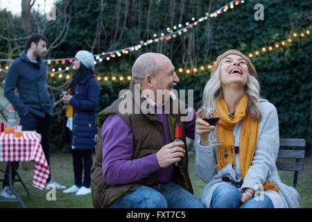 Coppia matura al garden party di gettare la testa indietro ridendo Foto Stock