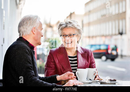 Romantico coppia senior presso cafè sul marciapiede tenendo le mani Foto Stock