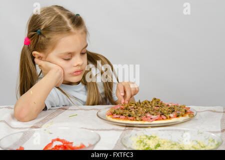 Piccolo bambino di sei anni ragazza seduta al tavolo e preleva pizza incompiuto Foto Stock