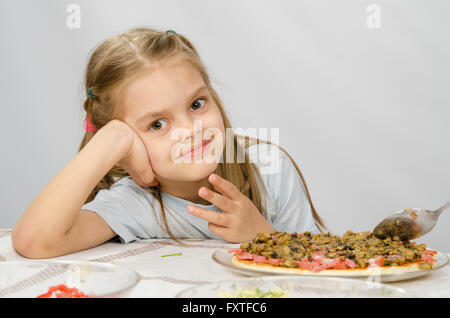 Piccolo bambino di sei anni ragazza seduta al tavolo in attesa per la preparazione di pizza Foto Stock