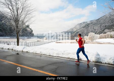 Runner maschio lungo la strada in inverno, Lago Kawaguchiko, il Monte Fuji, Giappone Foto Stock Runner maschio lungo la strada in inverno, Lago Kawaguchiko, il Monte Fuji, Giappone Foto Stock