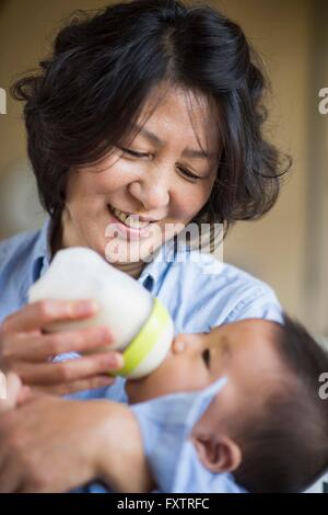 Nonna alimentazione di latte al nipote Foto Stock