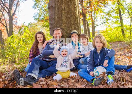 Ritratto di famiglia seduta nella foresta, accanto a tree Foto Stock