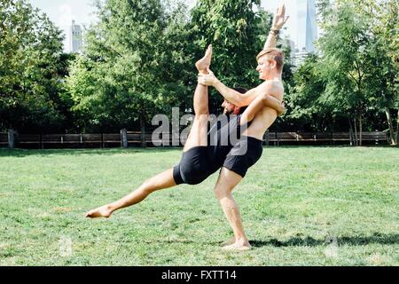 Due uomini a praticare yoga sollevare in posizione di stazionamento Foto Stock