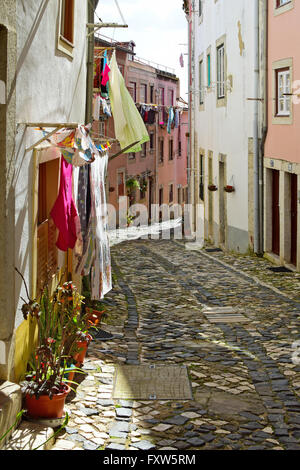 Una stretta strada nel quartiere di Alfama a Lisbona, Portogallo Foto Stock