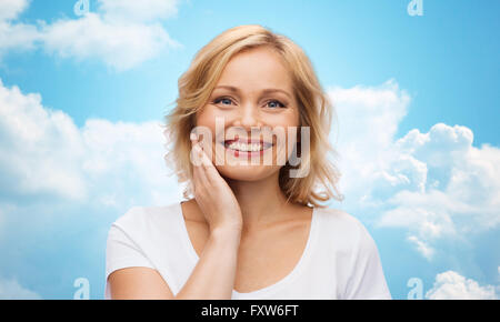 Donna sorridente in t-shirt bianco toccando il suo volto Foto Stock