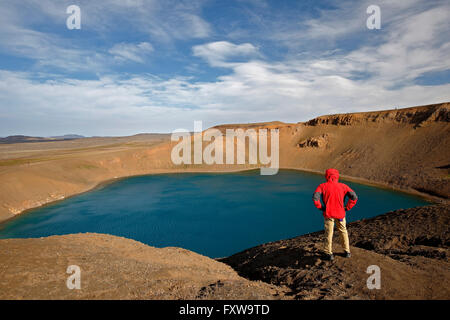 Escursionista ammirando il cratere di esplosione Viti, Vulcano Krafla, vicino Reykjahlid, Islanda Foto Stock