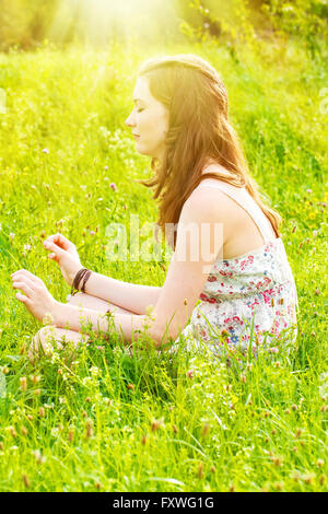 Giovane donna meditando su un verde prato Foto Stock