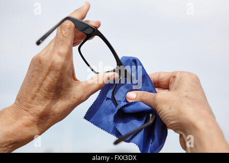 Womans pulizia delle mani degli occhiali con un panno Foto Stock