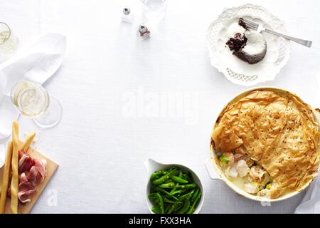 Vista aerea del tavolo per la cena con pollo e Torta di porri, fagioli verdi e budino di cioccolato dessert Foto Stock