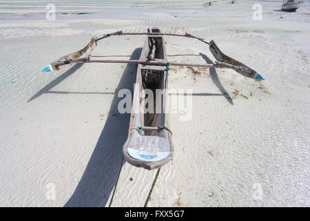 Dhow imbarcazione in legno che giace a secco a bassa marea su una spiaggia all'Oceano Indiano vicino a Zanzibar, Tanzania Foto Stock