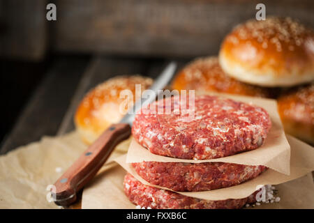 Materie di macinato di manzo bistecca di carne bistecche e hamburger panini su sfondo di legno, pronti per la cottura Foto Stock