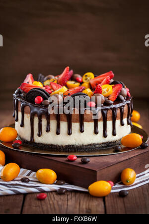 Due strati di cioccolato decorate cheesecake con fragole fresche, kumquat e cioccolato Foto Stock