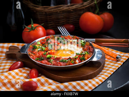Shakshuka - uova fritte con pomodoro, cipolla, pepe e spezie in padella di ferro, stile scuro Foto Stock