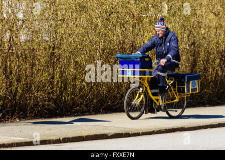 Lund, Svezia - 11 Aprile 2016: la vera vita in città. Giovane maschio portalettere facendo il suo giro in bici. Foto Stock