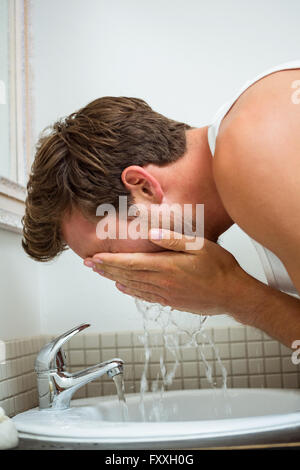 Lavaggio uomo il suo volto in bagno Foto Stock