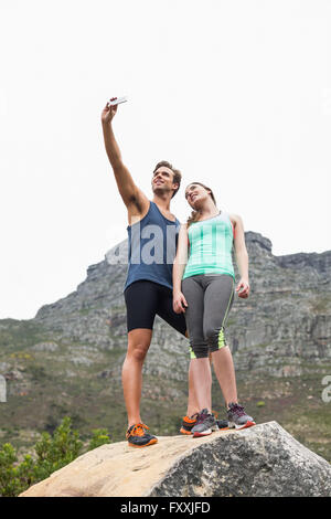 Basso angolo vista del giovane tenendo selfie su roccia Foto Stock