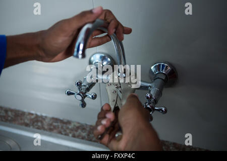 Close-up di plumber che fissa il dissipatore con la chiave Foto Stock