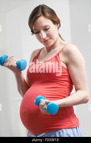 Donna incinta esercizio con pesi Foto Stock