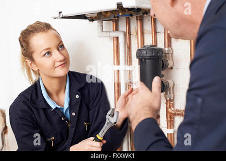 Trainee femmina Plumber lavorando sul centro di caldaia di riscaldamento Foto Stock