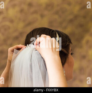 La stilista pinning di una sposa acconciatura e velo nuziale prima del matrimonio Foto Stock