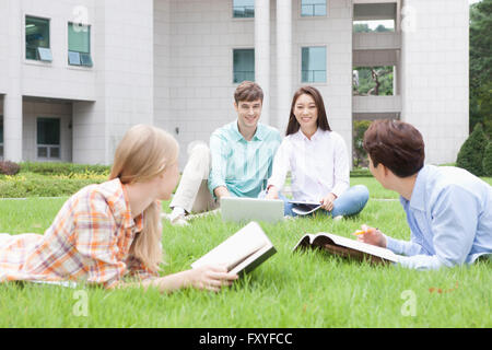 Gli studenti internazionali e nazionali gli studenti di college per studiare insieme seduto o disteso su un'erba del campus Foto Stock