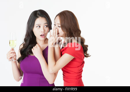 Ritratto di due giovani donne che parlano in un sussurro a parte Foto Stock