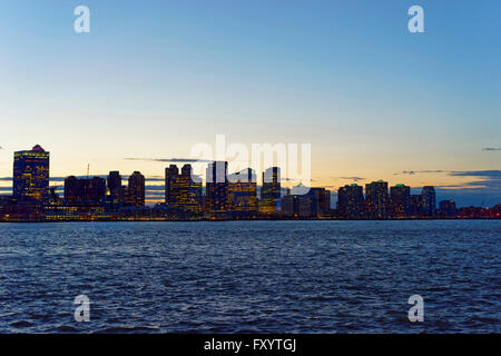 Vista dalla spianata di Lower Manhattan, New York, Stati Uniti d'America, dall'alto in Paulus Hook, Jersey City, New Jersey, USA. Grattacieli illuminata di sera. Fiume Hudson Foto Stock