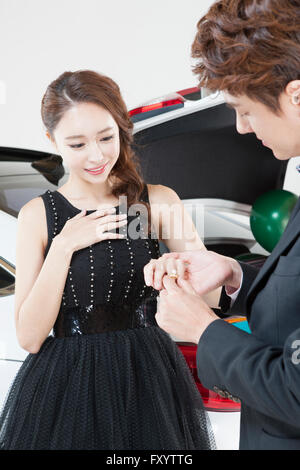 Giovane uomo mettendo un anello sul giovane donna sorridente del dito Foto Stock