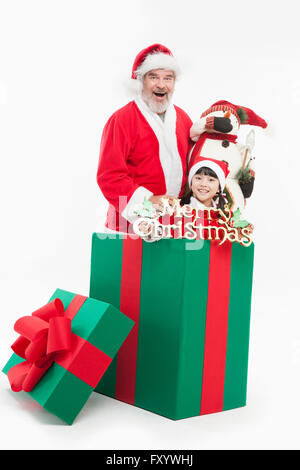 Ritratto di Santa sorridente e ragazza in posa con pupazzo di neve e le decorazioni di Natale in una grande scatola fissando sulla parte anteriore Foto Stock