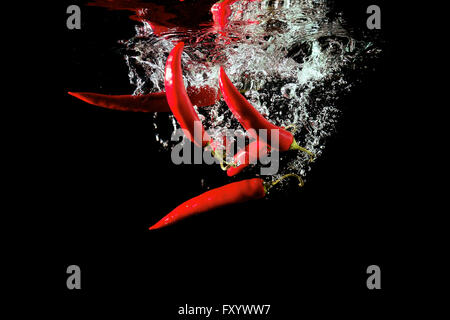 Diversi peperoni rossi caduti in acqua Foto Stock