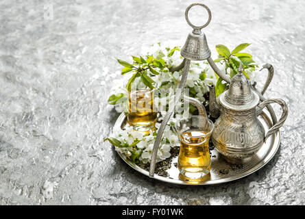 Bicchieri di tè e pot. Piatti d'argento. Vacanze orientali decorazioni con fiori. Foto Stock