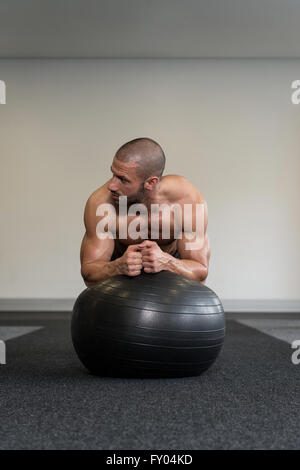 Giovane uomo esercizio Abs sulla sfera di postura di allenamento nel centro Fitness Foto Stock