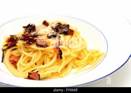 La tradizionale cucina italiana Spaghetti alla carbonara con pancetta, uova e formaggio parmigiano sulla piastra bianca. Foto Stock